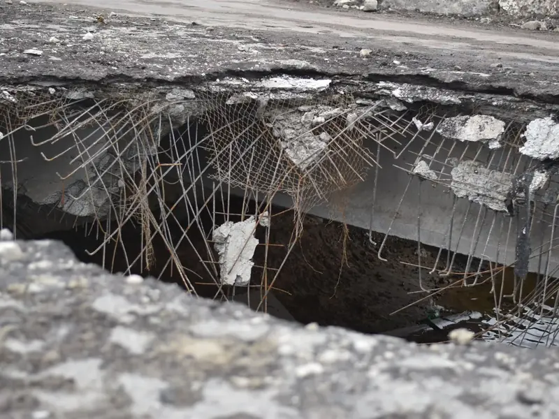 Laje de concreto rompida com armadura de aço exposta e enferrujada.